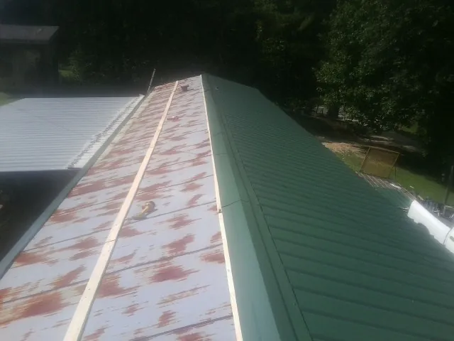 Old rusted panels beside newly installed green metal roofing — Wind Damage Roof Repair by Roofing Brothers in Wapakoneta
