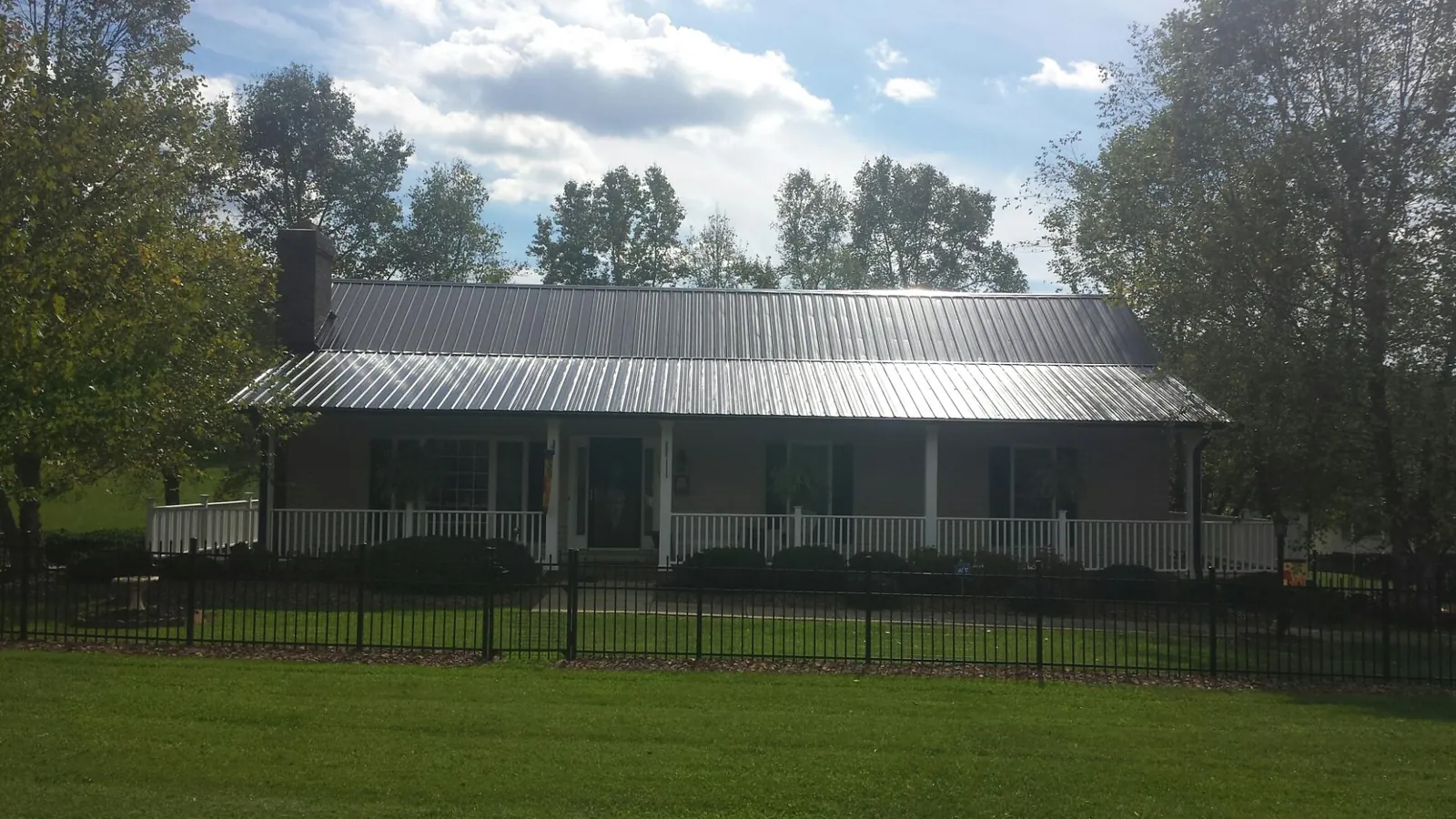 Gray metal roof on a brick ranch with a full width front porch — Gutter Guard Installation work by our crew in Wapakoneta