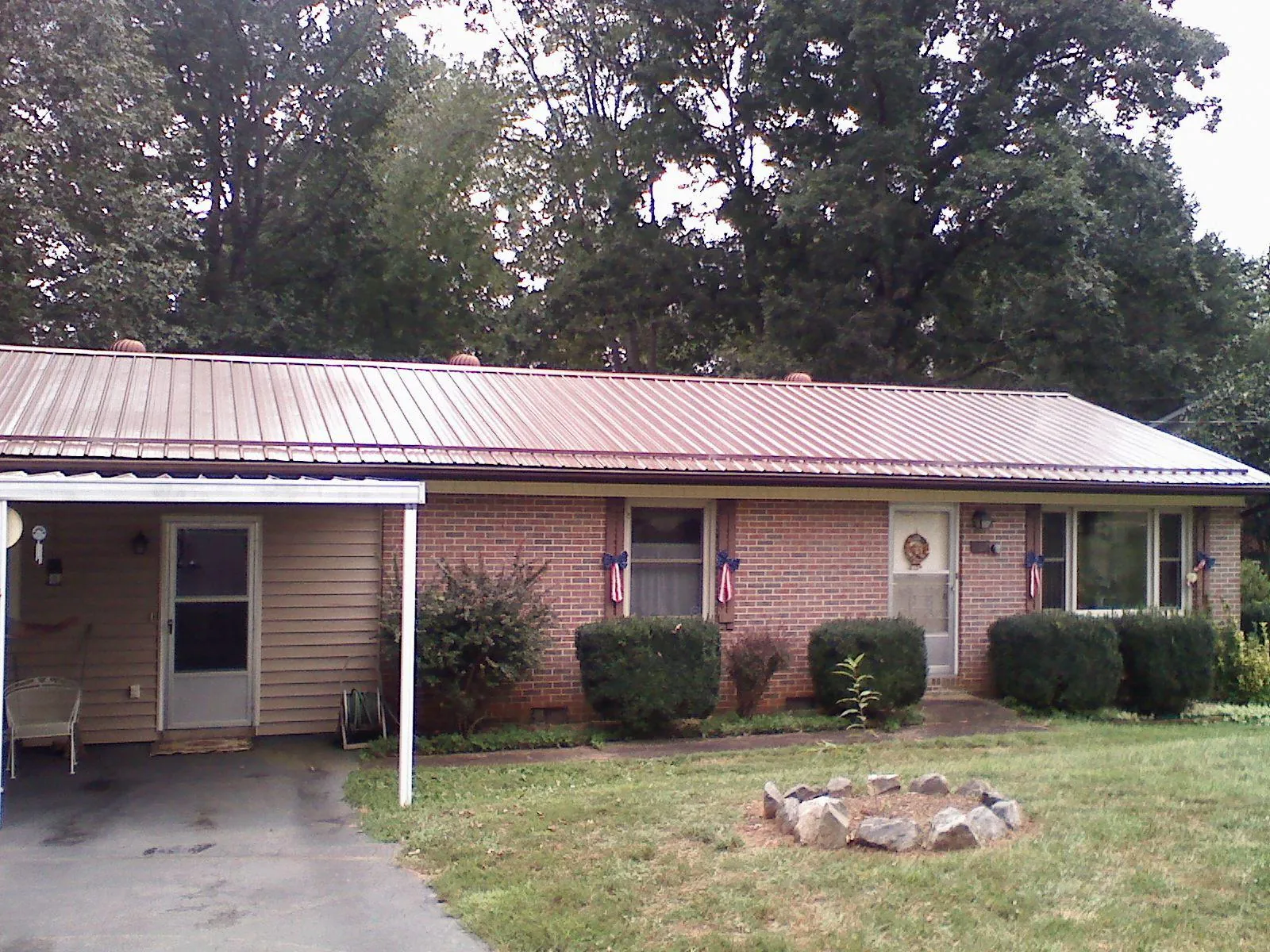 Bronze metal roof and carport on a brick ranch home — Roof Repair work by our crew in Wapakoneta