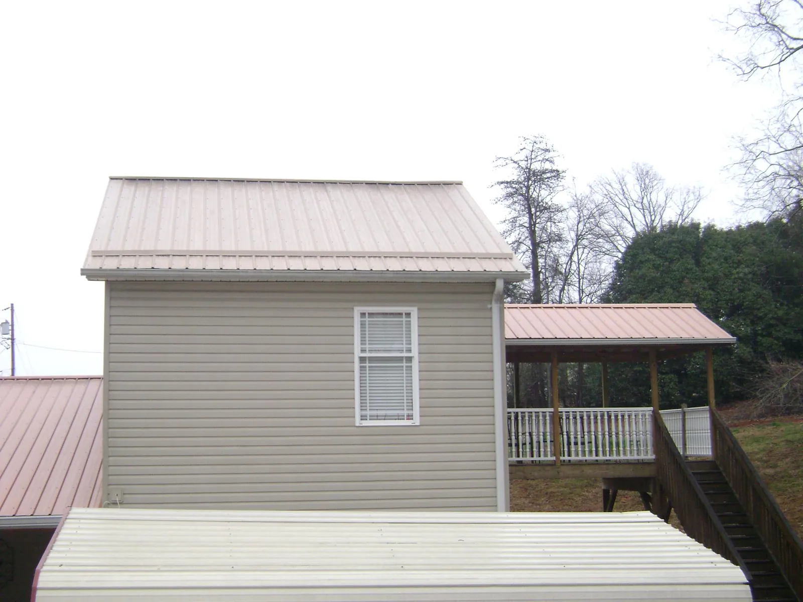 Tan metal roofs on a two story addition and attached porch, from a Roof Replacement job in Wapakoneta