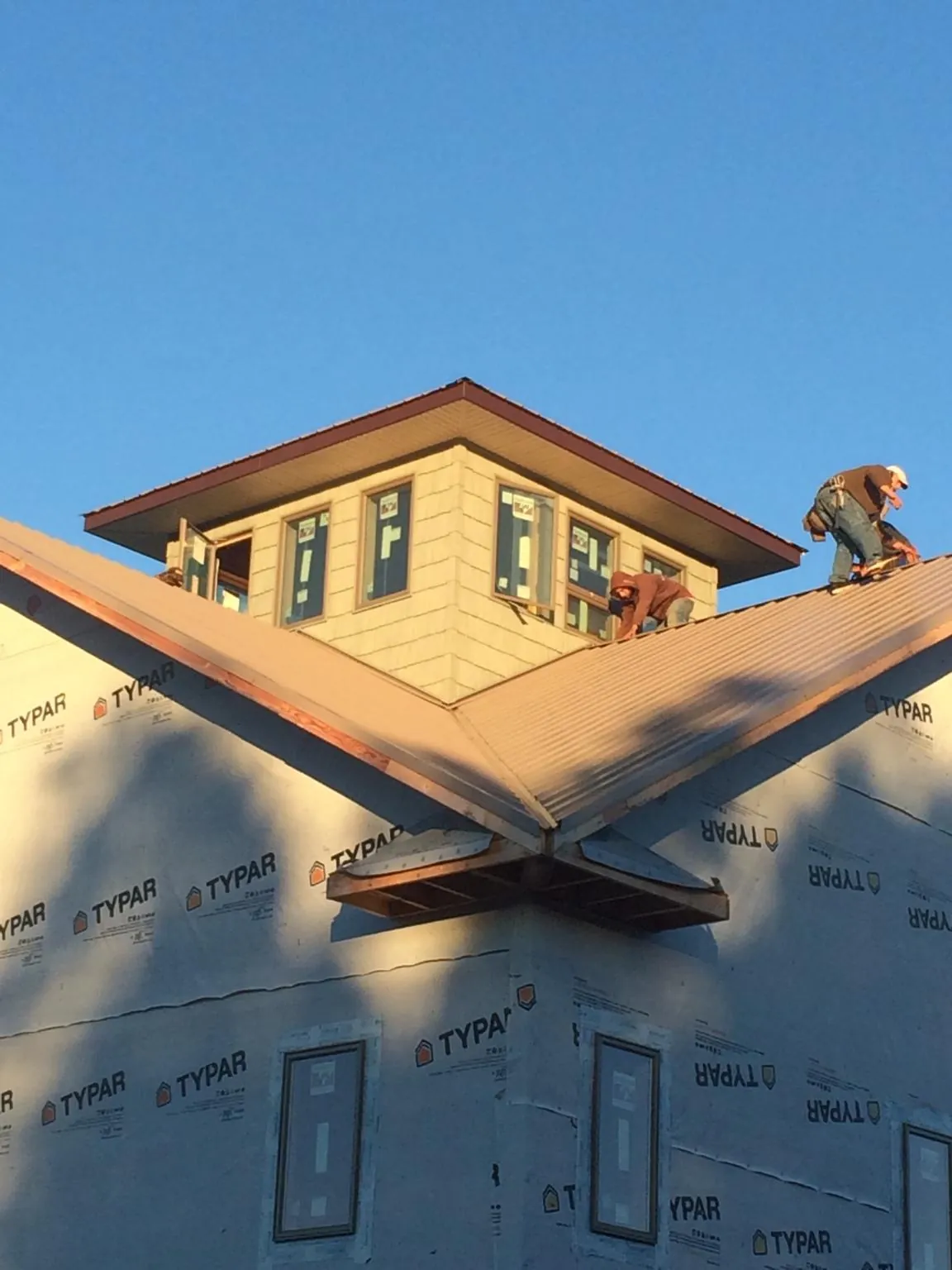 Roofers working around a rooftop cupola on a new metal roof at sunset — Roof Waterproofing in Wapakoneta by Roofing Brothers